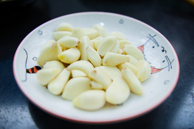 A bowl of peeled garlic in a small white bowl