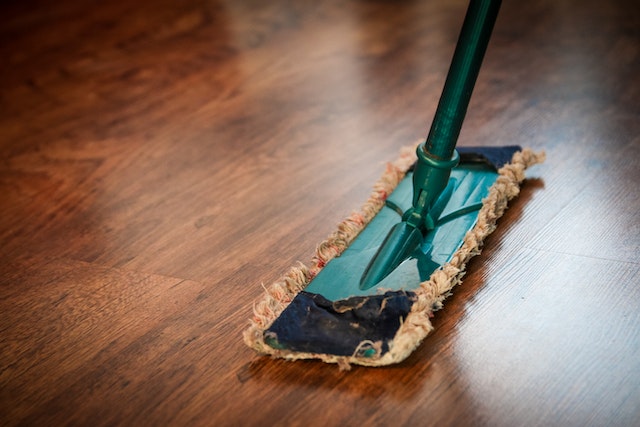 A dust mop cleaning up on a brown hardwood floor