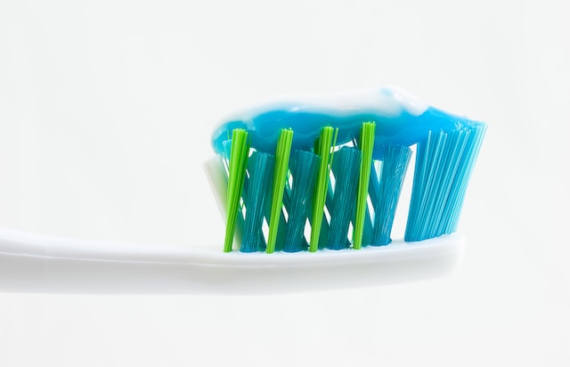 blue toothpaste on a green and blue bristled toothbrush 