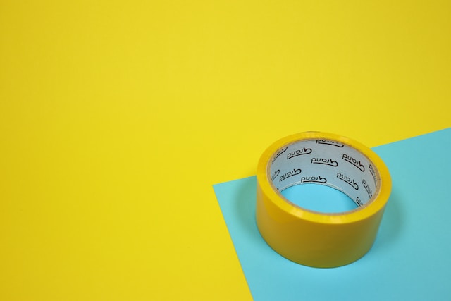 Yellow sticky tape, a component of pet-safe ant traps, against a blue and yellow background