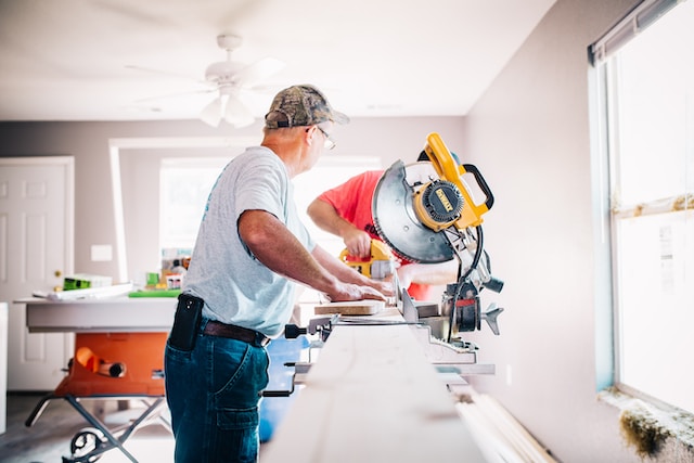 Two people working on wooden boards inside a home