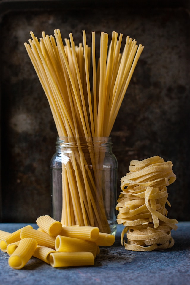 Different types of pasta in glass jars and on the table