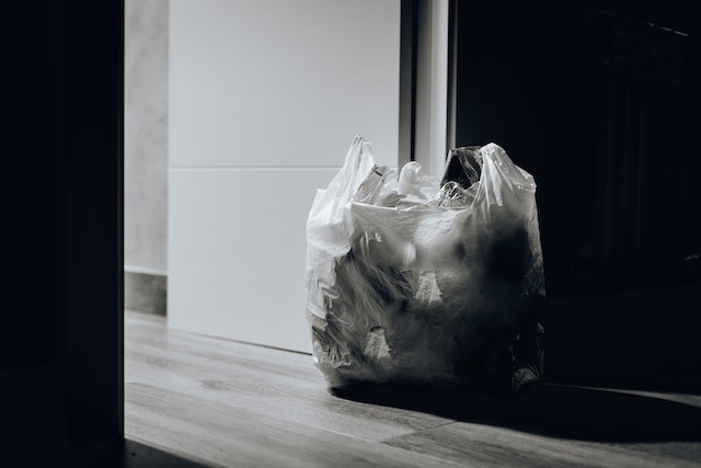 An open trashbag filled with waste by a doorway