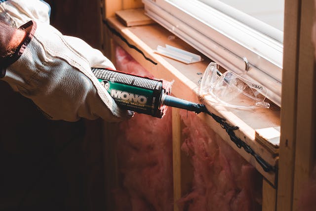 Repair person caulking a window