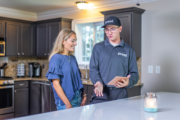 proof. tech speaking to a client in her kitchen